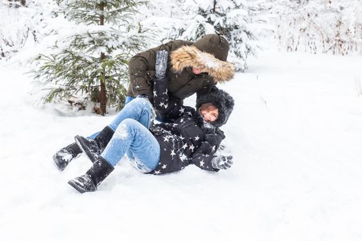 Fun, season and leisure concept - love couple plays winter wood on snow.