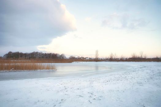 Beautiful winter landscape at sunset with fog and snow covering farmland and river in the Netherlands beautiful colors in nature winter