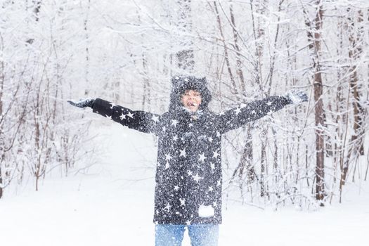 Happy girl throw up a snow in a winter forest