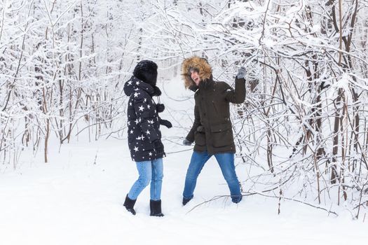 Young couple in love walks in the snowy forest. Active winter holidays