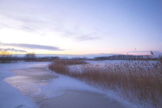 Beautiful winter landscape at sunset with fog and snow covering farmland and river in the Netherlands beautiful colors in nature winter