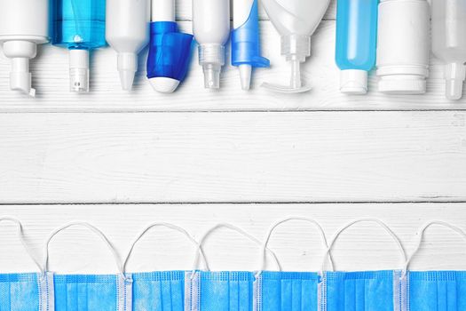 Row of bottles with hand sanitizers, liquid soap and medical preparations on white wooden background