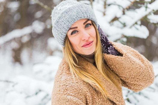 Beautiful winter portrait of young woman in the winter snowy scenery.