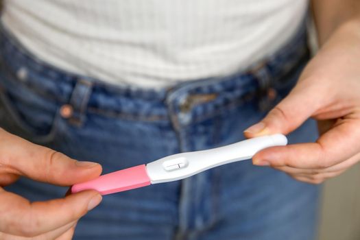 Young woman holding negative pregnancy test,home pregnancy test showing negative result close up modern design