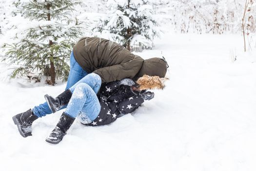 Lifestyle, season and leisure concept - Funny couple playing snowball in winter park.