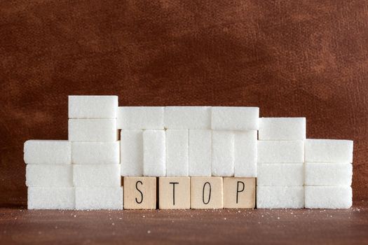 Pile or wall of sugar cubes and stop word in block letters as advise on addiction calories excess and sweet unhealthy food abuse causing health problem and overweight background concept.