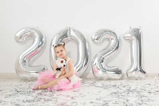 New year, holidays and celebration concept - Little girl sitting near with numbers balloons 2021