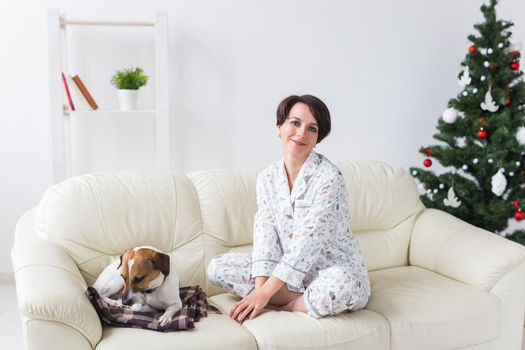 Happy young woman with lovely dog in living room with christmas tree. Holidays.