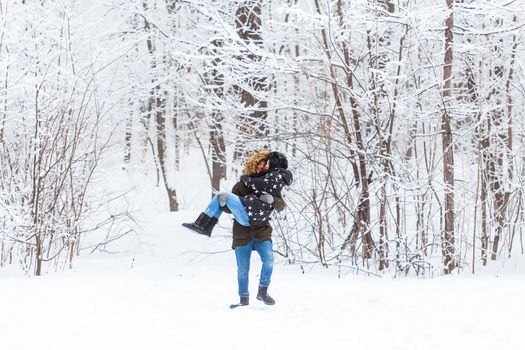 Young couple in love walks in the snowy forest. Active winter holidays