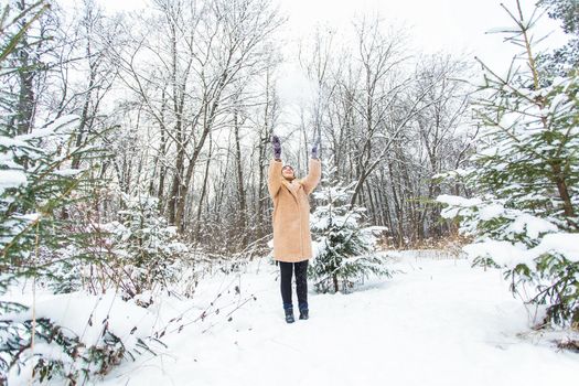 Young woman throwing snow in the air at sunny winter day, she is happy and fun