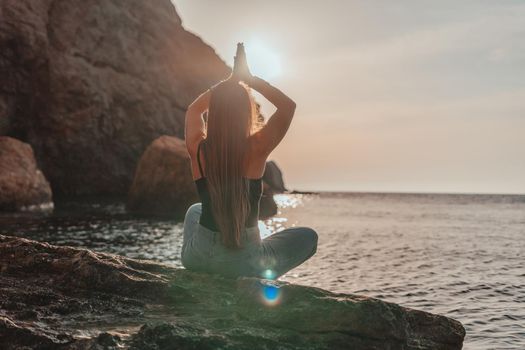 Young woman in swimsuit with long hair practicing stretching outdoors on yoga mat by the sea on a sunny day. Women's yoga fitness pilates routine. Healthy lifestyle, harmony and meditation concept.