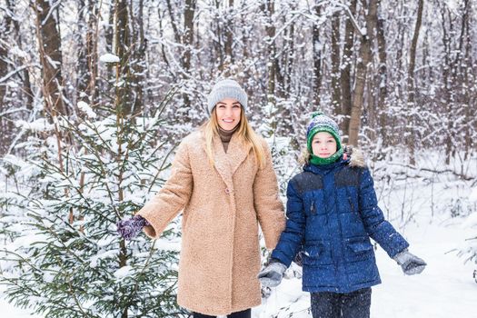 Parenting, fun and season concept - Happy mother and son having fun and playing with snow in winter forest.