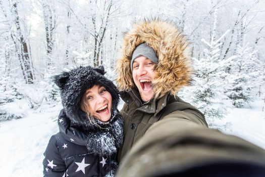 Season and relationship concept - Funny couple taking selfie in the winter time.