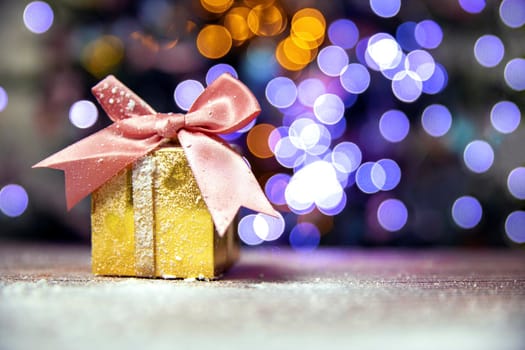 Merry Christmas, New Year, gifts in gold boxes with pink bow in the snow, bokeh Christmas tree background with copy space, Holiday,present concept space for text