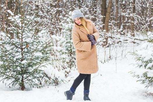Beautiful winter portrait of young woman in the winter snowy scenery.
