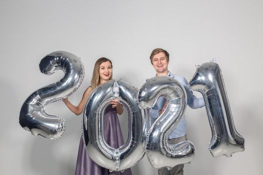 Party, people and new year holidays concept - woman and man celebrating new years eve 2021.