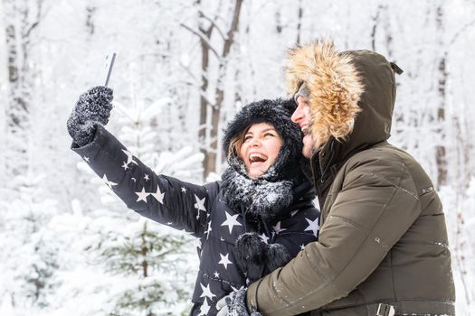 Season and relationship concept - Funny couple taking selfie in the winter time.