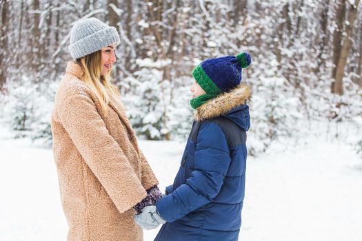 Portrait of happy mother with child son in winter outdoors. Single parent.