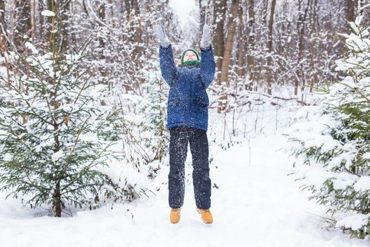 Young boy plays with snow, have fun, smiles. Teenager in winter park. Active lifestyle, winter activity, outdoor winter games, snowballs.