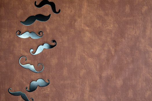 Black mustache and hat on brown leather background texture with copy space, International Men's day and Fathers Day concept space for text