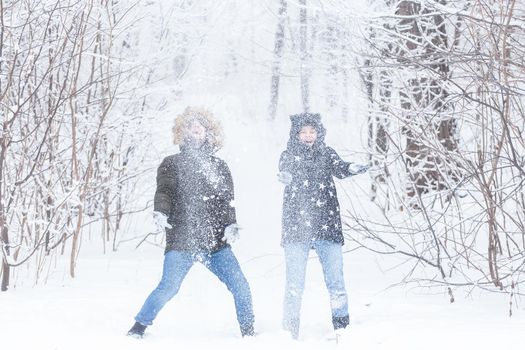 Young couple playing with snow in winter park.