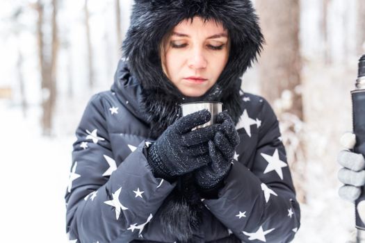 Young couple in love drink a hot drink from a thermos and enjoy winter nature