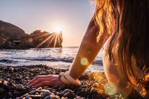 Young woman in swimsuit with long hair practicing stretching outdoors on yoga mat by the sea on a sunny day. Women's yoga fitness pilates routine. Healthy lifestyle, harmony and meditation concept.