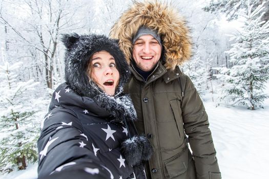 Season and relationship concept - Funny couple taking selfie in the winter time.