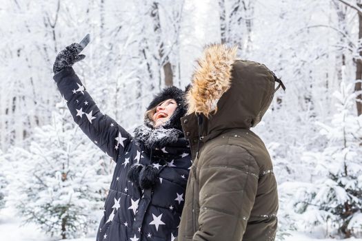 Season, love, technology and leisure concept - happy couple taking selfie by smartphone over winter.