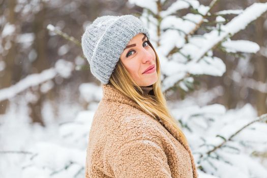 Beautiful winter portrait of young woman in the winter snowy scenery.