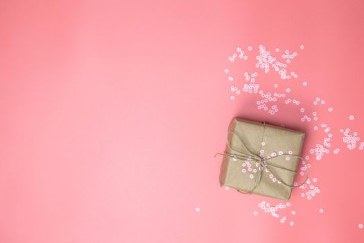 Gift box with brown Kraft paper surrounded with pink daisies and flatlay pink background, spring, Happy Mothers Day, Valentines Day and other Holliday concept top view, Modern design copy space