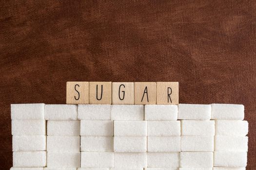 Sugar cubes wall with the text Sugar on brown natural background texture, Health,diabetes,medical,sugar,sweet.junk food concept copy space