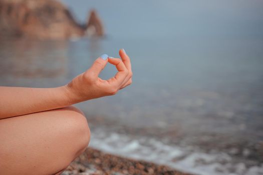 Young woman in swimsuit with long hair practicing stretching outdoors on yoga mat by the sea on a sunny day. Women's yoga fitness pilates routine. Healthy lifestyle, harmony and meditation concept.