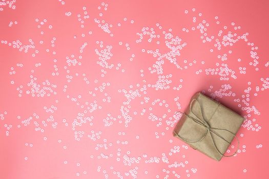 Gift box with brown Kraft paper surrounded with pink daisies and flatlay pink background, spring, Happy Mothers Day, Valentines Day and other Holliday concept top view, Modern design copy space