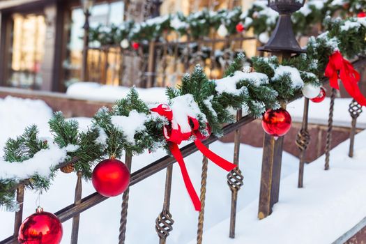 Christmas cityscape - decorating railing porch on the eve of the holiday. Christmas baubles and tapes. Winter holidays