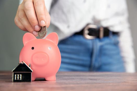 Money saving for buying a new house in pink piggy bank , real estate,mortgage,loans,business concept with space for text copy space on wooden table