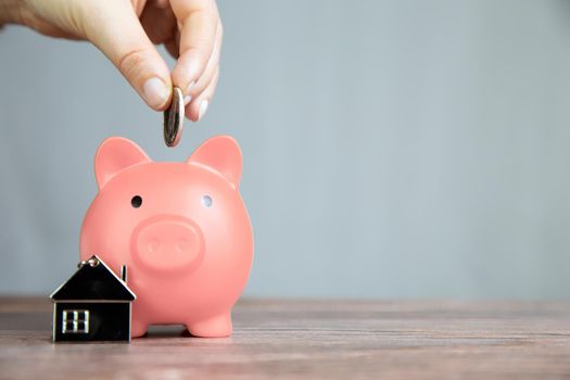 Money saving for buying a new house in pink piggy bank , real estate,mortgage,loans,business concept with space for text copy space on wooden table