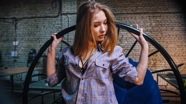 Young attractive woman in open shirt standing in workshop. Portrait