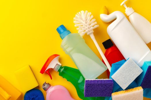 Set of cleaning supplies on yellow color background, top view
