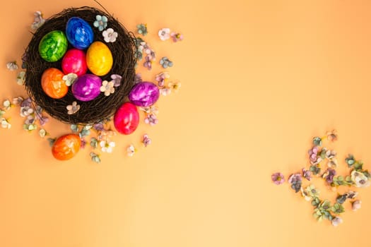 Colorful painted Easter Egg Nest with orange pastel colored background top view, Happy Easter Holliday concept background with Copy space spring bright colors design space for text
