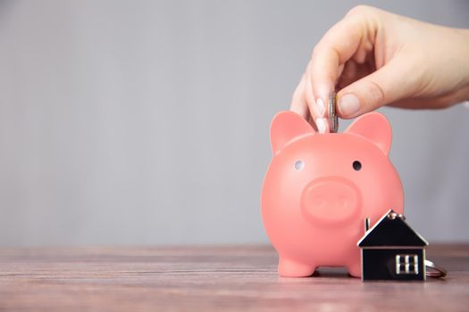 Money saving for buying a new house in pink piggy bank , real estate,mortgage,loans,business concept with space for text copy space on wooden table