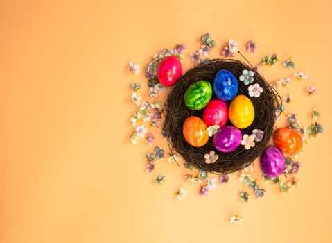 Colorful painted Easter Egg Nest with orange pastel colored background top view, Happy Easter Holliday concept background with Copy space spring bright colors design space for text