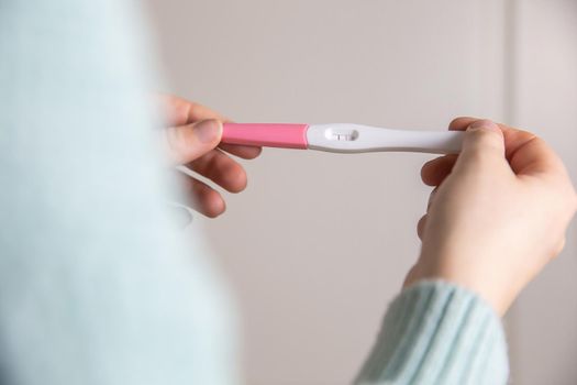 Happy young woman holding a positive pregnancy test close-up bright colors modern stylish design beautiful nature