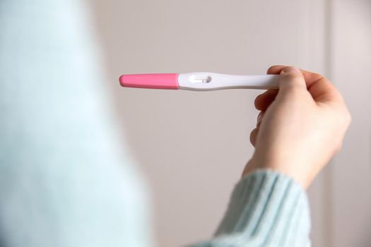 Young woman holding negative pregnancy test,home pregnancy test showing negative result close up modern design