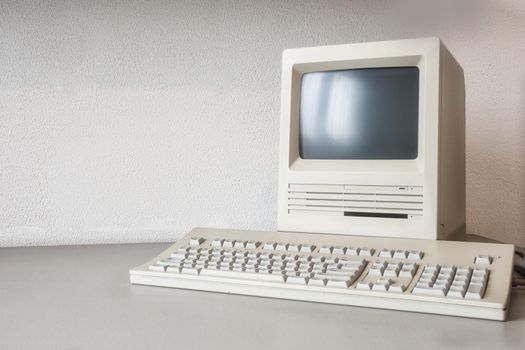 Old vintage monitor and computer on desk, retro workplace with copy space business, technology,internet concept near white wall