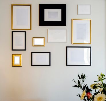 Empty gold and black photo and picture frames on white wall, mock up for your photos or text, copy space modern design luxury decoration closeup