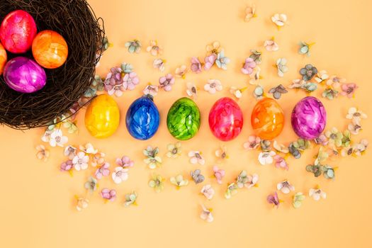 Colorful Easter eggs homemade painted top view flatlay on pastel orange peach background bright fresh design, Happy Easter, spring concept copy space