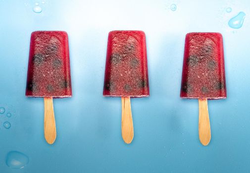 Homemade blueberry ice cream or popsicles on blue background with water drops frozen fruit juice, retro style, top view summer,ice cream,food concept fresh colors