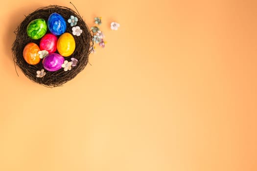 Colorful painted Easter Egg Nest with orange pastel colored background top view, Happy Easter Holliday concept background with Copy space spring bright colors design space for text