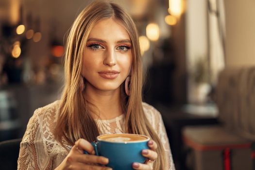 Beautiful young woman sitting in coffee shop enjoying her drink. High quality photo